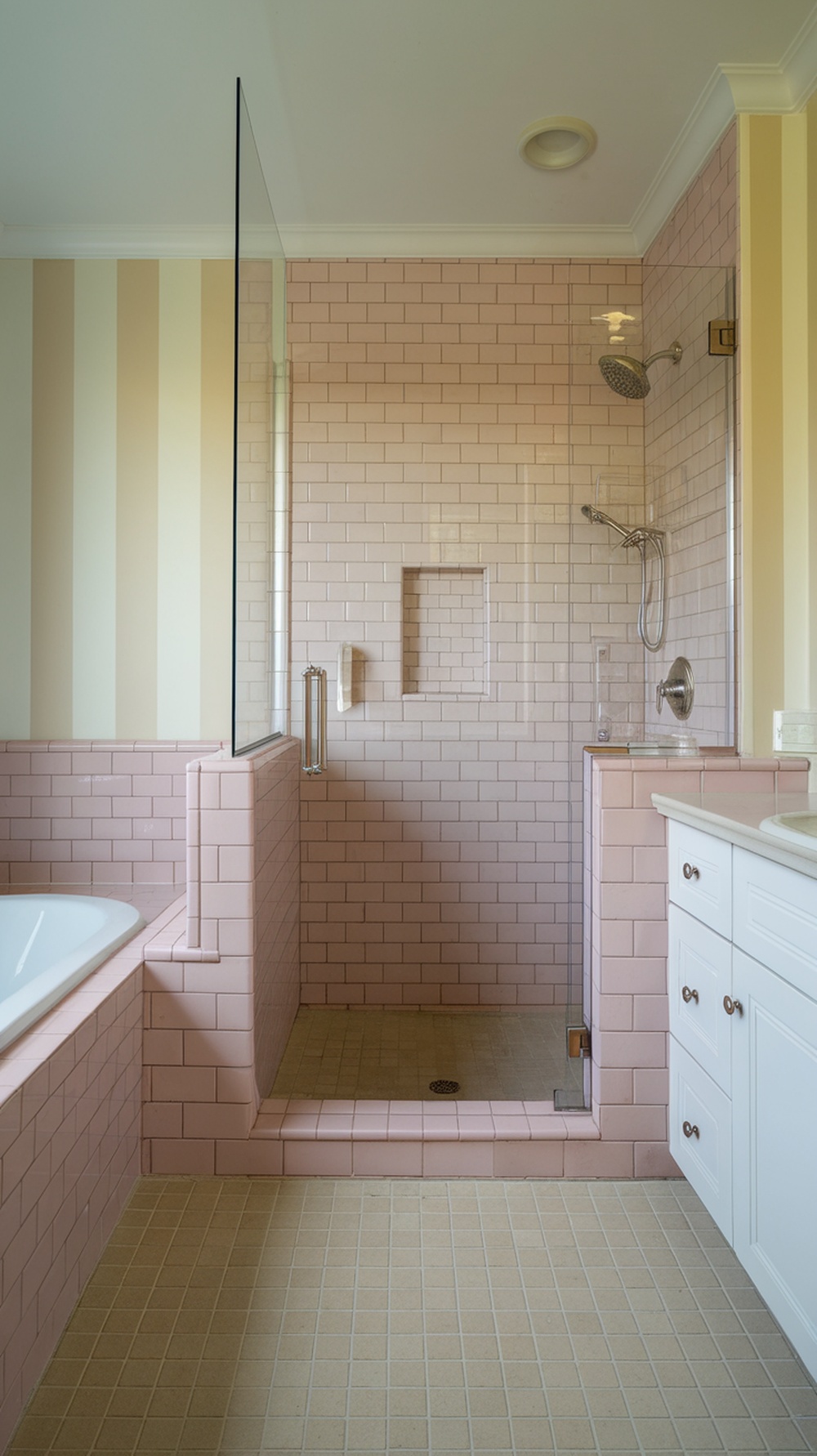 A modern pink bathroom featuring a shower space with pink tiles, a glass wall, and white cabinetry.