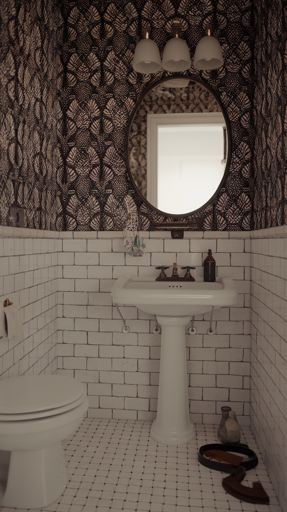 A vintage black and white bathroom featuring patterned wallpaper, white subway tiles, and a round mirror.